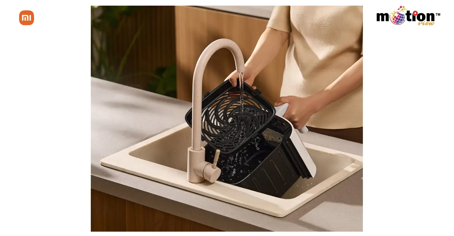Cleaning the removable non-stick grill tray and basket of the Mijia Smart Air Fryer S1 under a kitchen tap.