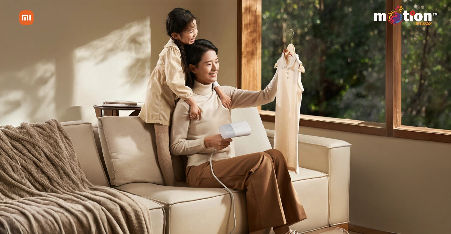 Lifestyle image showing a woman using the white Xiaomi Handheld Garment Steamer 2 to vertically steam a child's dress in a living room setting.